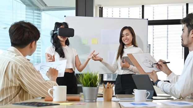 Diverse young businesspeople brainstorming together in the office and using virtual reality headset.