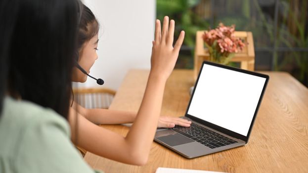 Happy preteen girl learning online at virtual class on laptop computer at home. Concept of Virtual education, homeschooling.