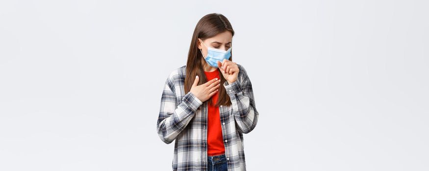 Coronavirus outbreak, leisure on quarantine, social distancing and emotions concept. Woman in medical mask coughing, feeling sick, touching lungs, have covid-19 symptoms, being ill.