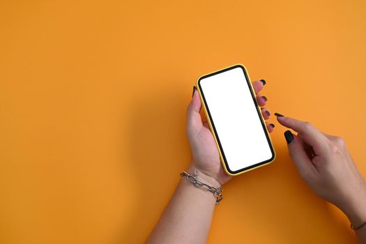 Woman holding mockup smart phone with blank screen on yellow background.