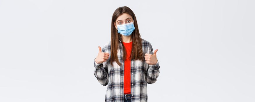 Coronavirus outbreak, leisure on quarantine, social distancing and emotions concept. Very good congratulations. Supportive cute woman in medical mask show thumb-up, like and approve.