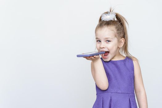 cute playful little girl wants to eat smartphone. place for text, copy space