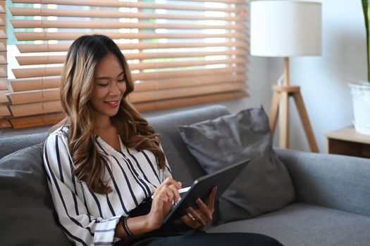 Happy young woman chatting with friends in social network, watching movie on digital tablet.