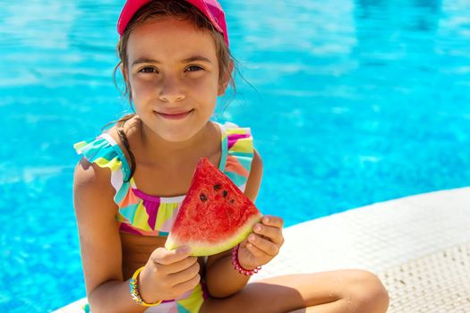 The child eats a watermelon near the pool. Selective focus. Kid.