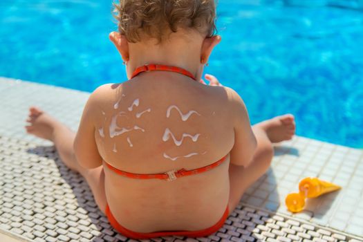 Sunscreen on the back of the child. Selective focus. Kid.