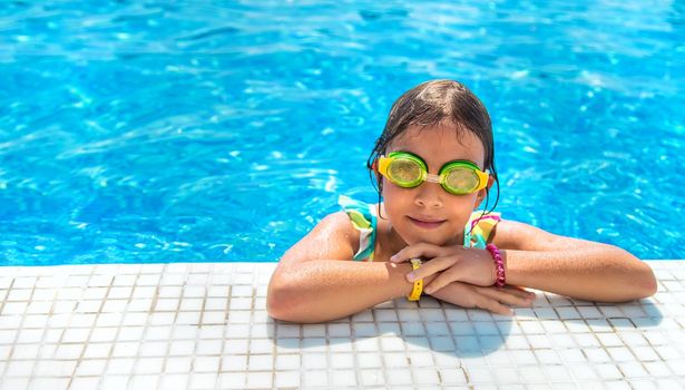 A child with glasses dives into the pool. Selective focus. Kid.