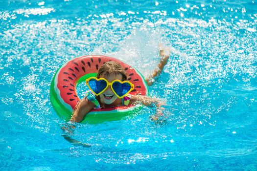 The child in the pool swims in a circle. Selective focus. Kid.