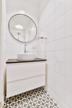 Sink with tap and liquid soap hanging on tiled wall under mirror in contemporary restroom at home