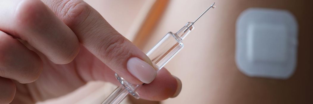 Close-up of woman holding syringe filled with medicine liquid and patch on arm. Female after getting first dose of vaccine. Covid cure, vaccination concept