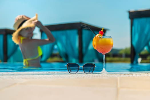 Woman with cocktail near the pool. Selective focus. Drink.