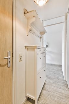 Light narrow hallway with many doors in white walls and glowing lamp over lumber floor