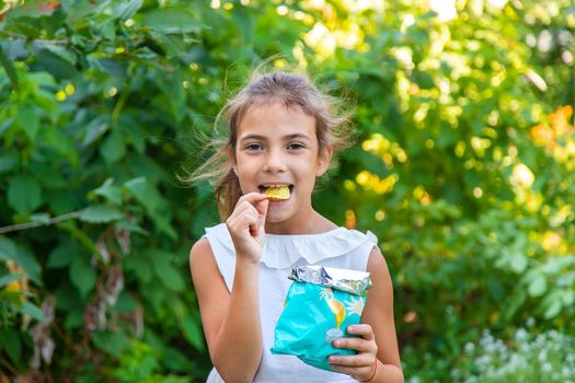 The child is eating chips. Selective focus. Kid.