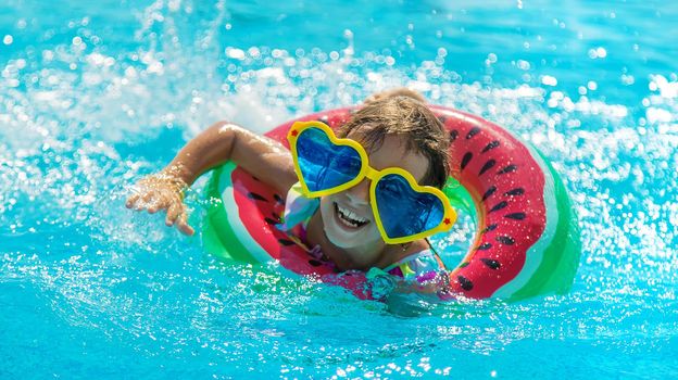 The child in the pool swims in a circle. Selective focus. Kid.