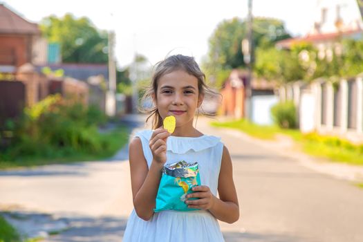 The child is eating chips. Selective focus. Kid.