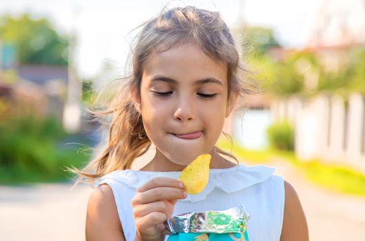 The child is eating chips. Selective focus. Kid.