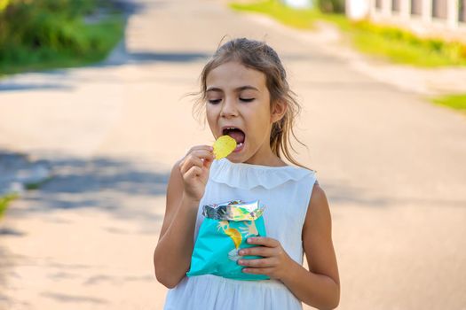 The child is eating chips. Selective focus. Kid.