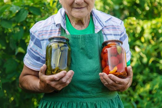 Grandma cans tomatoes and cucumbers for the winter. Selective focus. Food.