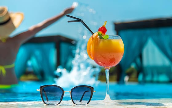 Woman with cocktail near the pool. Selective focus. Drink.