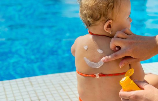 Mother smeared sunscreen on the back of the child. Selective focus. Baby.