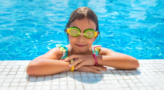 A child with glasses dives into the pool. Selective focus. Kid.