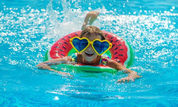 The child in the pool swims in a circle. Selective focus. Kid.