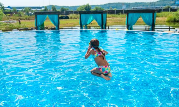 The child jumps dives into the pool. Selective focus. Kid.