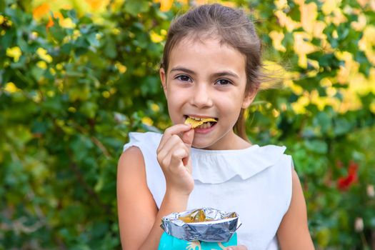 The child is eating chips. Selective focus. Kid.