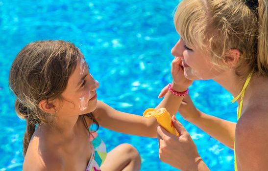 Mother smears sunscreen on the child face. Selective focus. Kid.