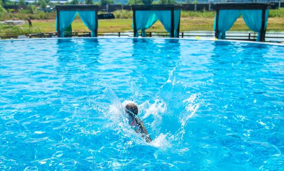 The child jumps dives into the pool. Selective focus. Kid.