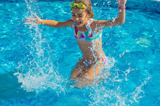A child in the pool splashes water. Selective focus. Kid.