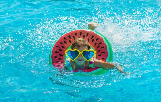 The child in the pool swims in a circle. Selective focus. Kid.