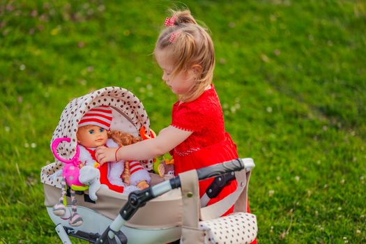 girl plays with her doll who is sitting in a toy stroller