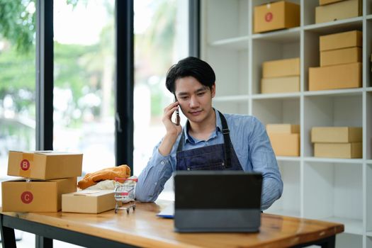 Asian SME business women use laptop computer checking customer order online shipping boxes at home. Starting Small business entrepreneur SME freelance. Online business, Work at home concept