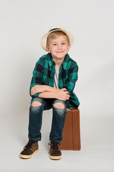 Portrait of cute stylish blond boy kid 7 years old wearing hat and checked shirt and jeans