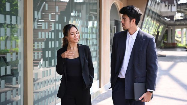 Shot of two young businesspeople talking about plans for the company while walking on city street.