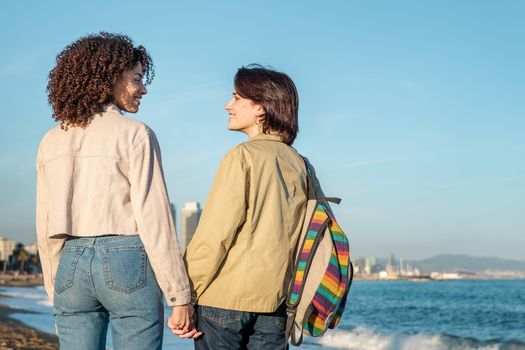young couple of homosexual women in love holding hands and looking into each other's eyes in Barcelona, gay friendly city, concept of sexual freedom and racial diversity