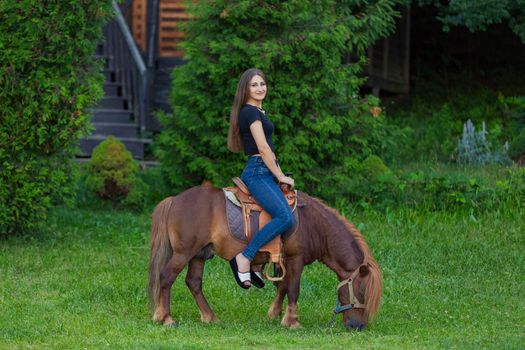 woman riding a pony on the lawn