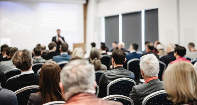 Speaker giving a talk in conference hall at business event. Rear view of unrecognizable people in audience at the conference hall. Business and entrepreneurship concept