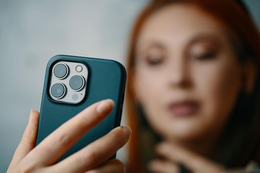 Fashionable girl takes selfie on iPhone 13 pro. Gadget with triple-lens camera. Close-up of woman's hand holding smartphone in case. Focus on foreground. Bishkek, Kyrgyzstan - January 24, 2022