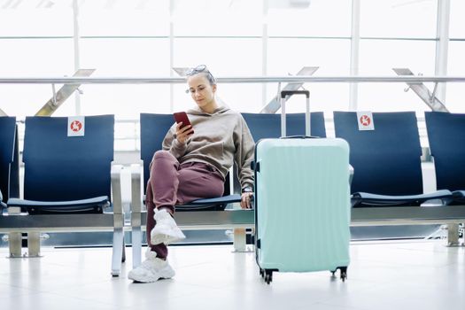 young woman with luggage sitting in the airport waiting room .Travel Concept.