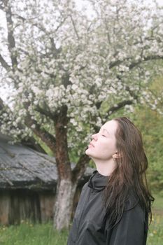 emotional portrait of a young woman standing alone under rain outdoors in spring