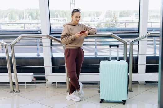 woman reading an SMS while standing at the airport . Travel Concept.