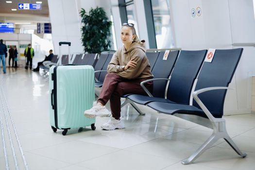 young woman with luggage sitting in the airport waiting room . side view.