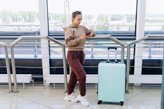 woman with a smartphone standing at the airport . Travel Concept.