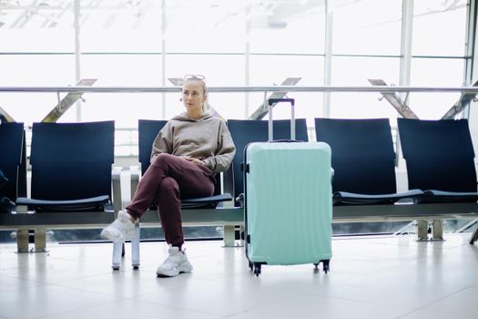 thoughtful woman with luggage sitting in the airport waiting room .Travel Concept.