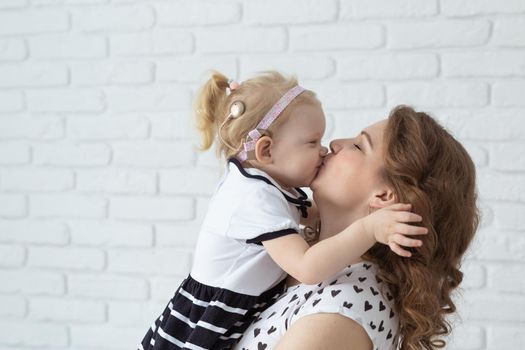 Mother helps her deaf baby daughter putting hearing aid in little girl's ear indoors - cochlear implant and innovative medical technologies