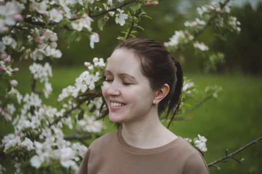 Romantic young woman in the spring garden among apple blossom