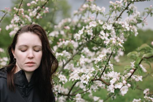 Romantic young woman in the spring garden among apple blossom