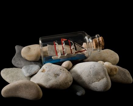 A boat in a bottle on stones, a souvenir on a black background