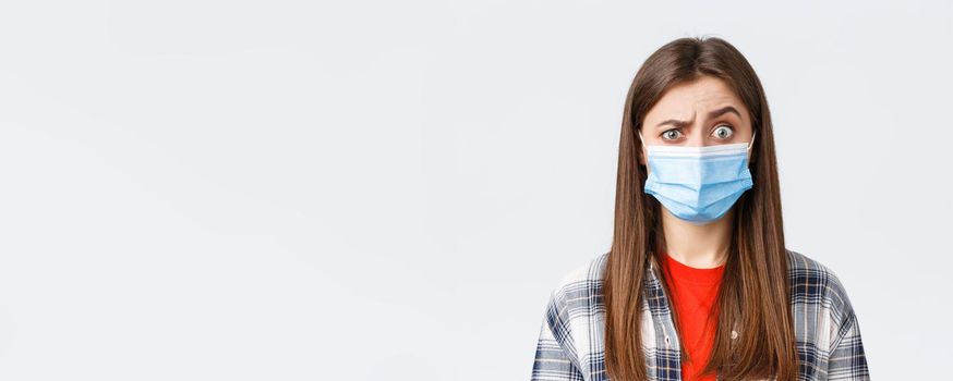 Coronavirus outbreak, leisure on quarantine, social distancing and emotions concept. Confused young woman cant understand what happening, look suspicious or surprised, wear medical mask.